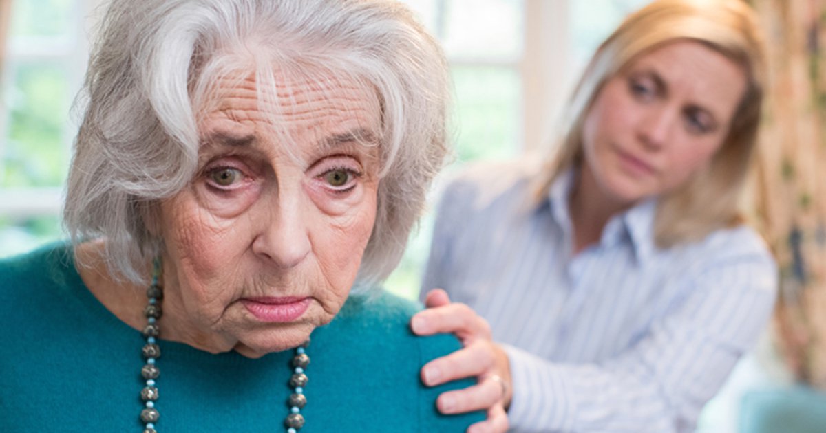 An older adult looking confused while a younger woman holds her shoulder from behind