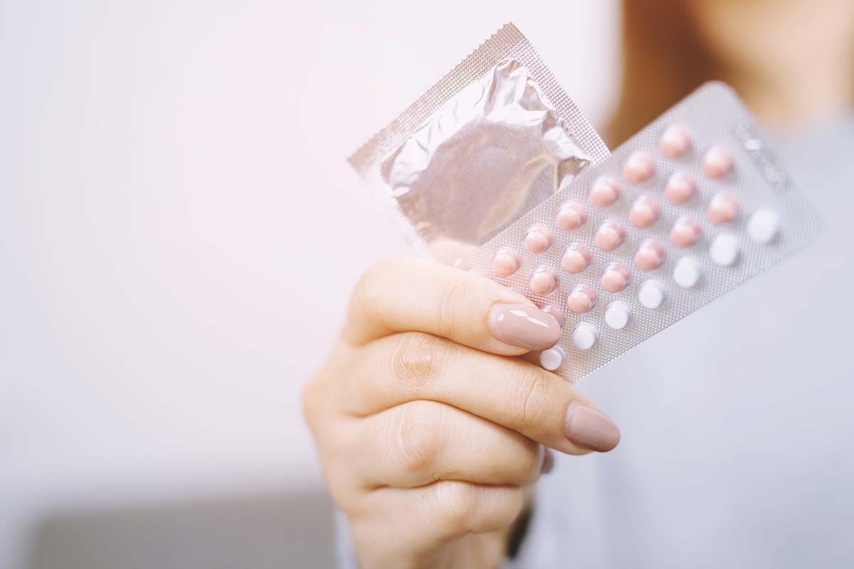 A woman holding a contraceptive pack and a pack of condom