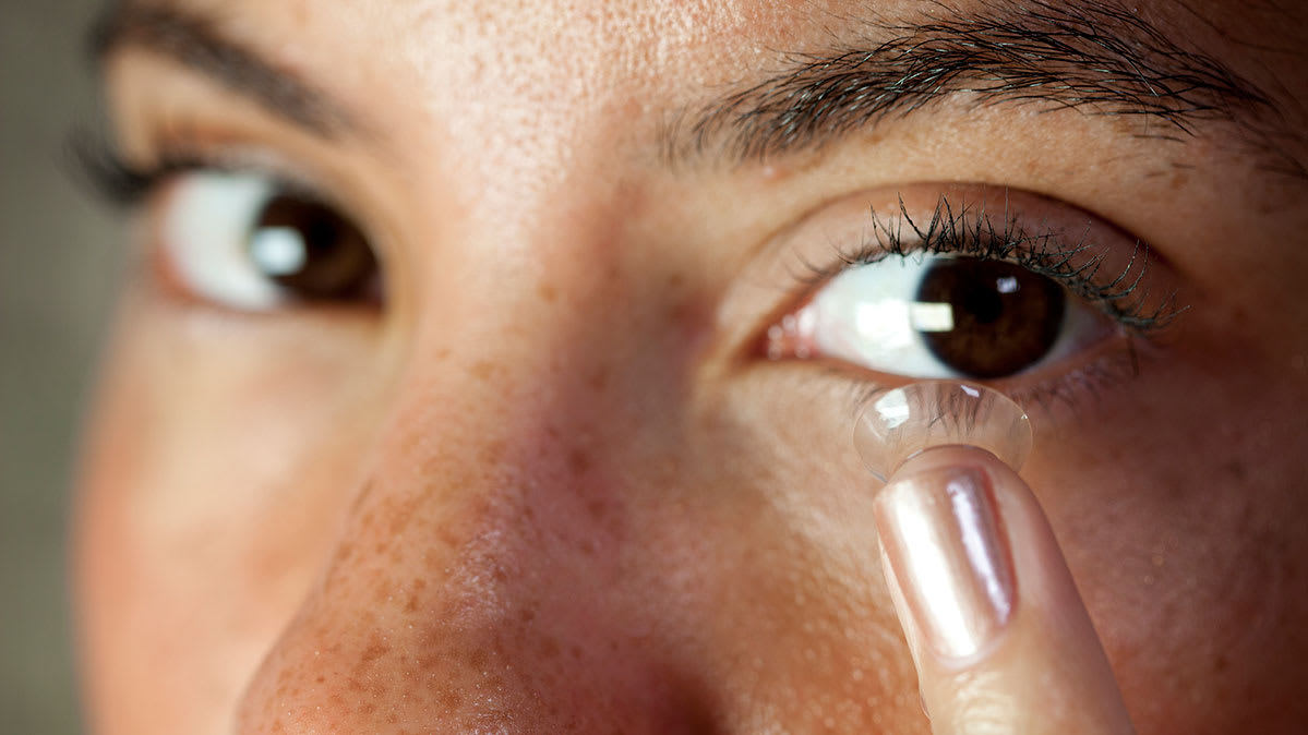 A lady putting on a contact lens on one of her eyes