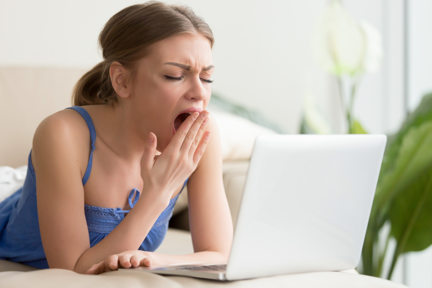 Tired woman is yawning after too long of work on a laptop
