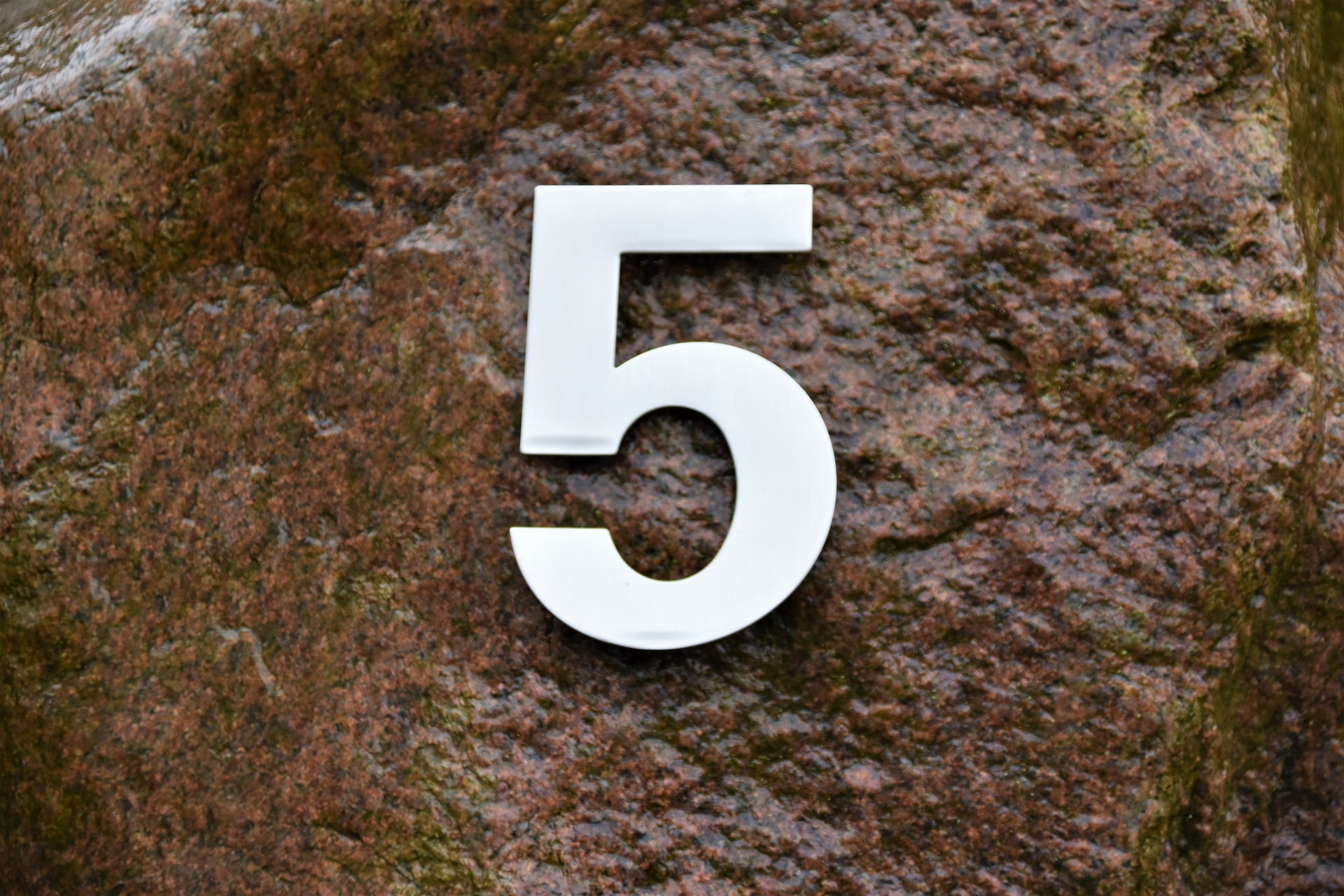 Number 5 in white color is shown on a brown rock