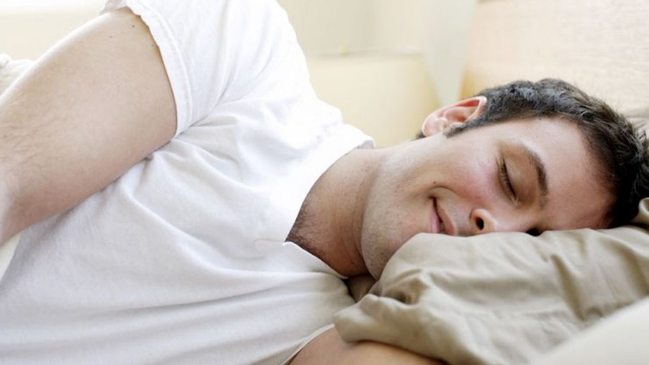 A man smiling while sleeping on a bed