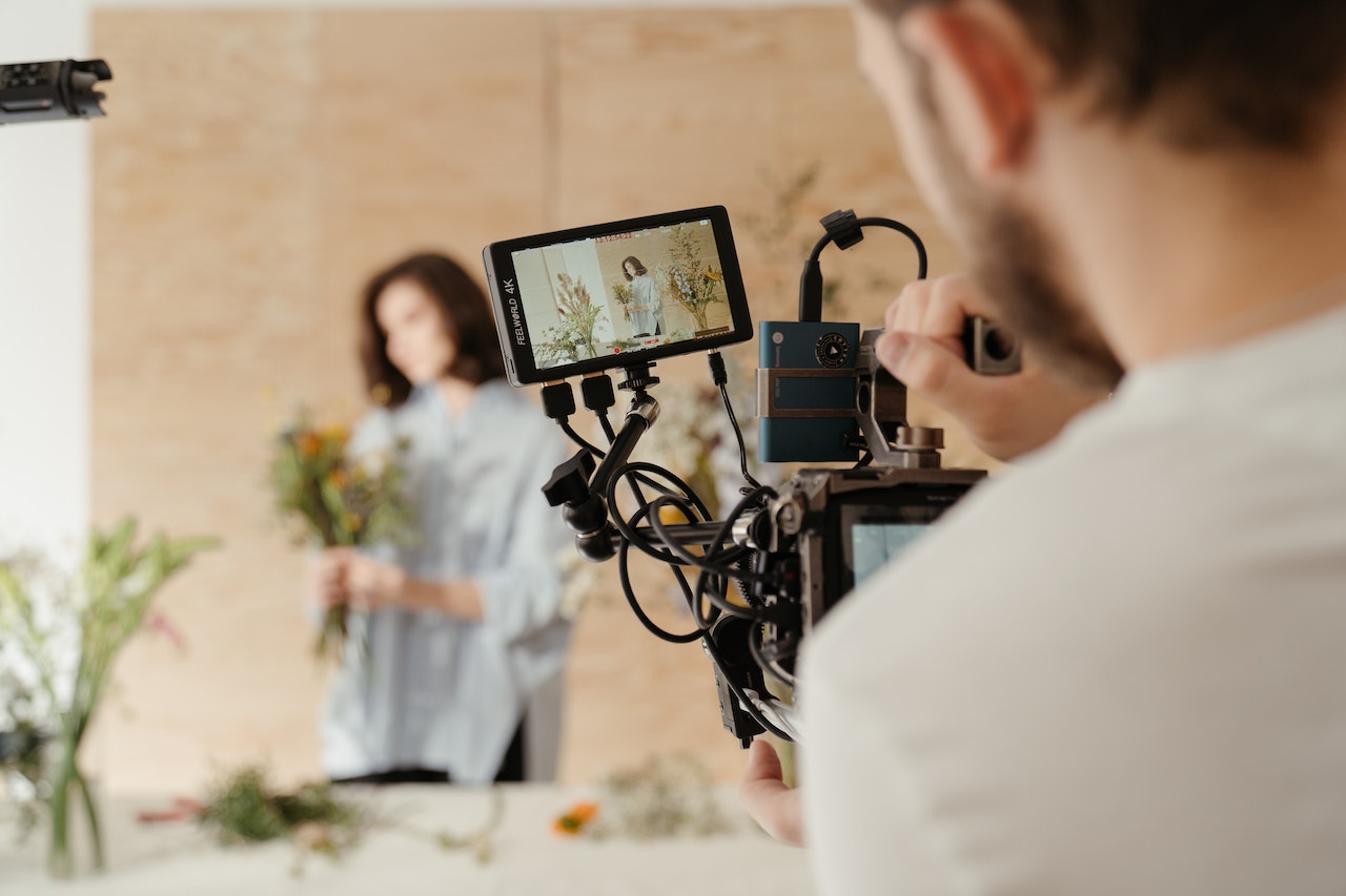 A Man Holding A Camera And Recording A Woman Arranging Flowers
