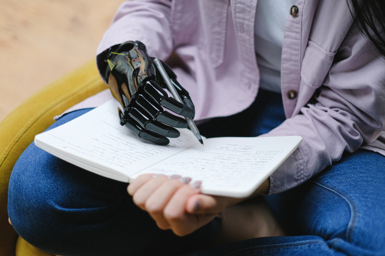 Woman with a modern prosthetic hand writing in notebook