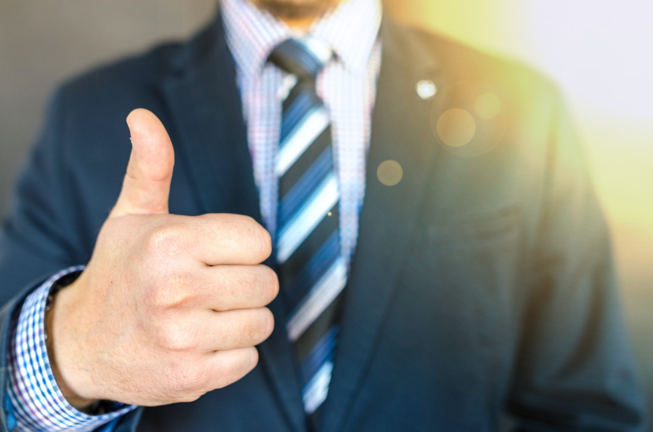 Man Wearing Black Suit Jacket While Doing A Thumbs Up Gesture