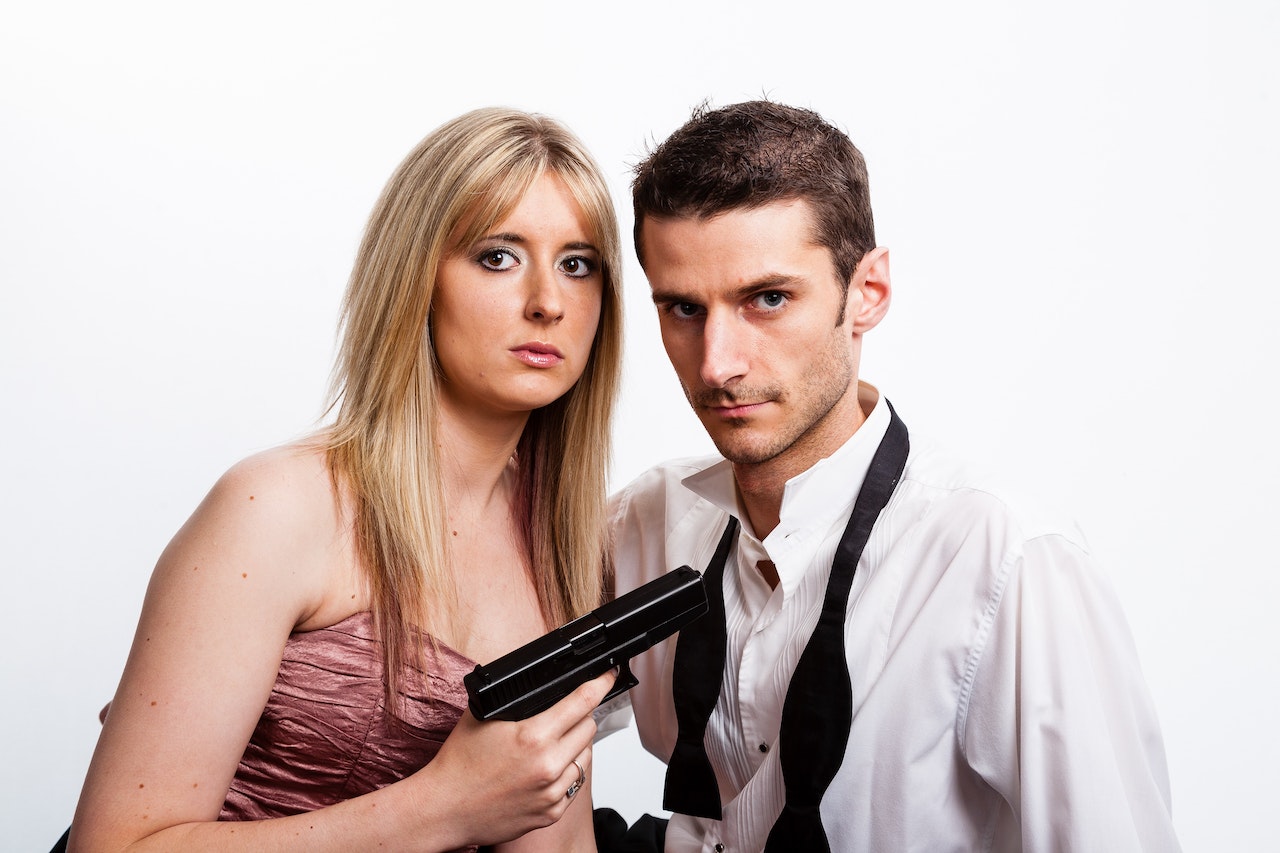 Woman Holding A Pistol And Pointing It To The Guy Beside Her