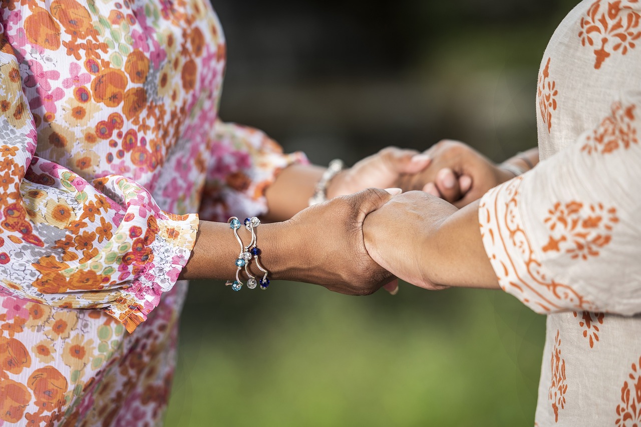 Two women holding their hands together in prayer
