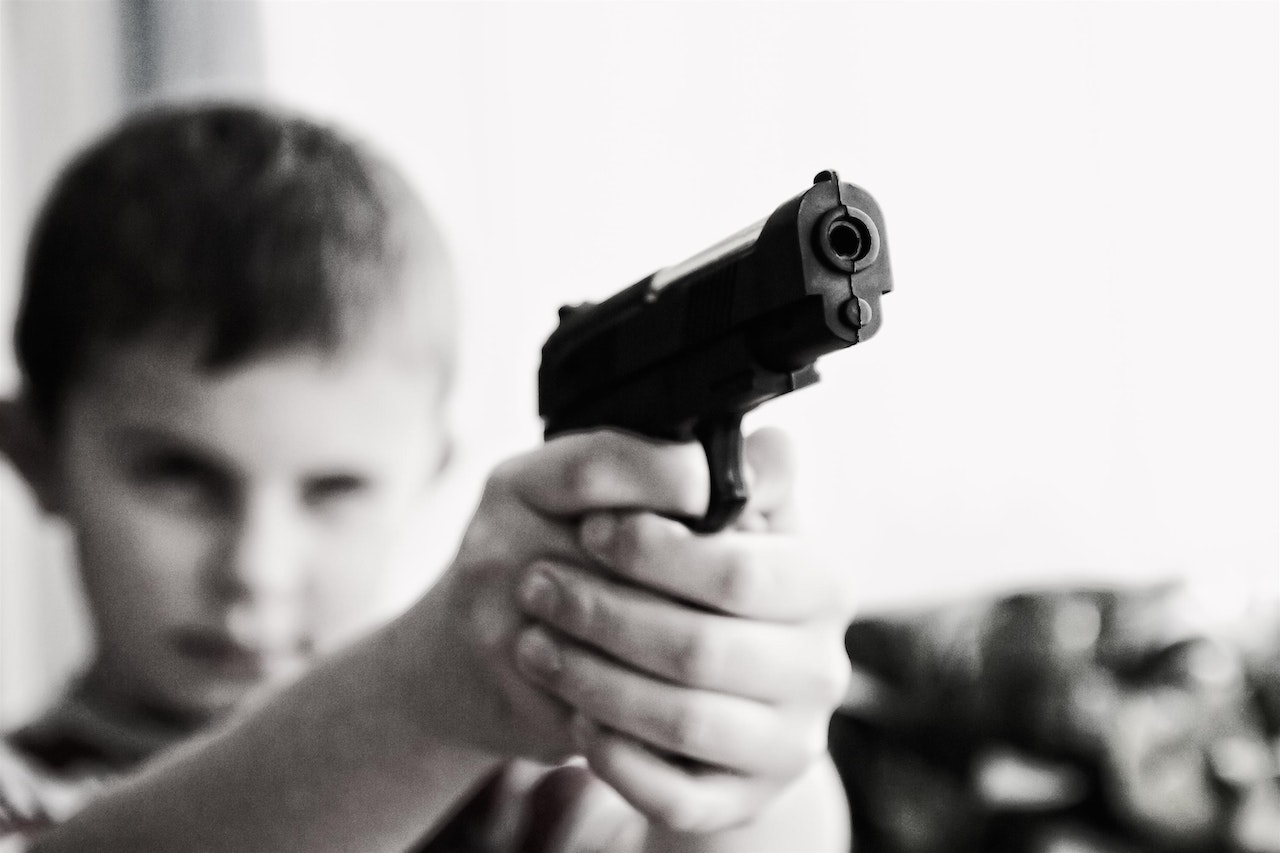 Grayscale Photo of a Boy Aiming Toy Gun Selective 