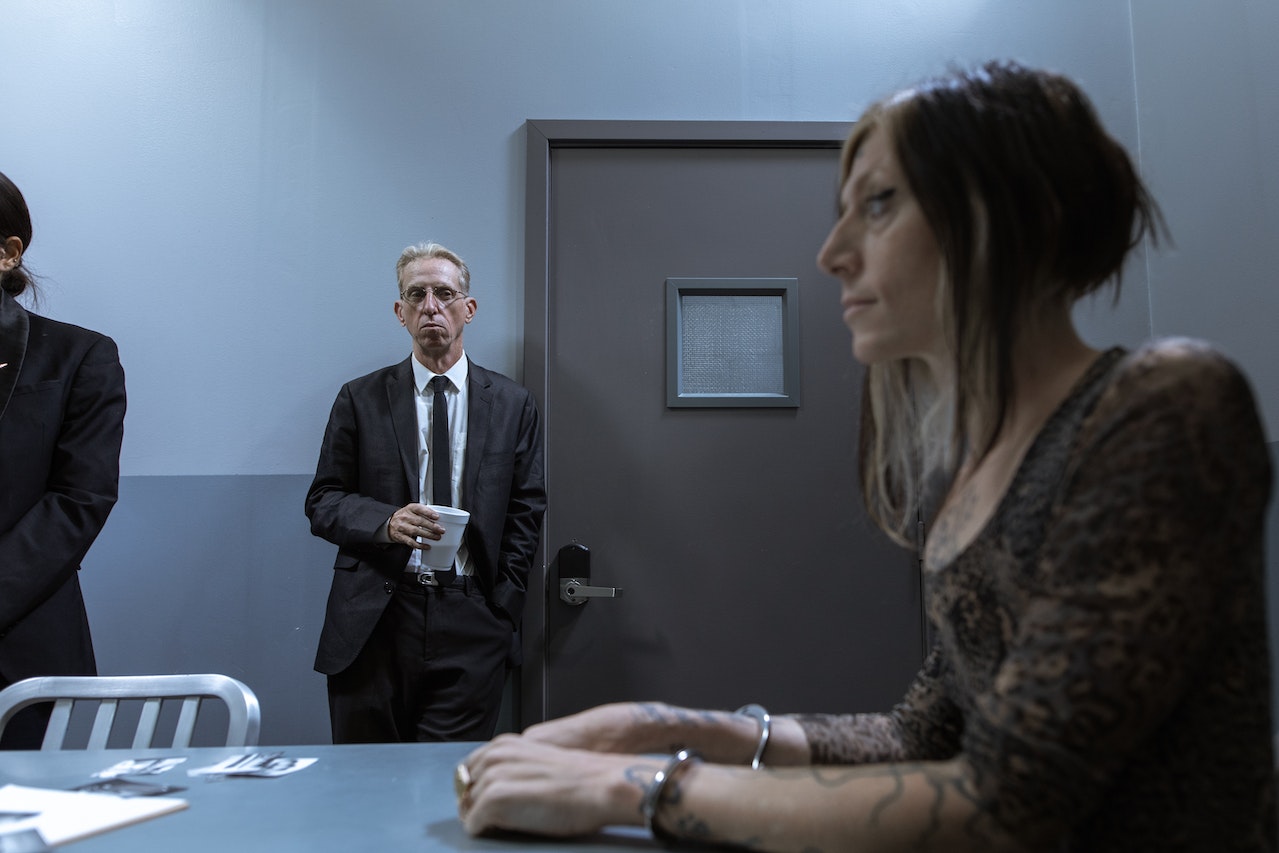 A Detective Standing by the Doorway Holding a Cup While Looking At A Person Of Interest