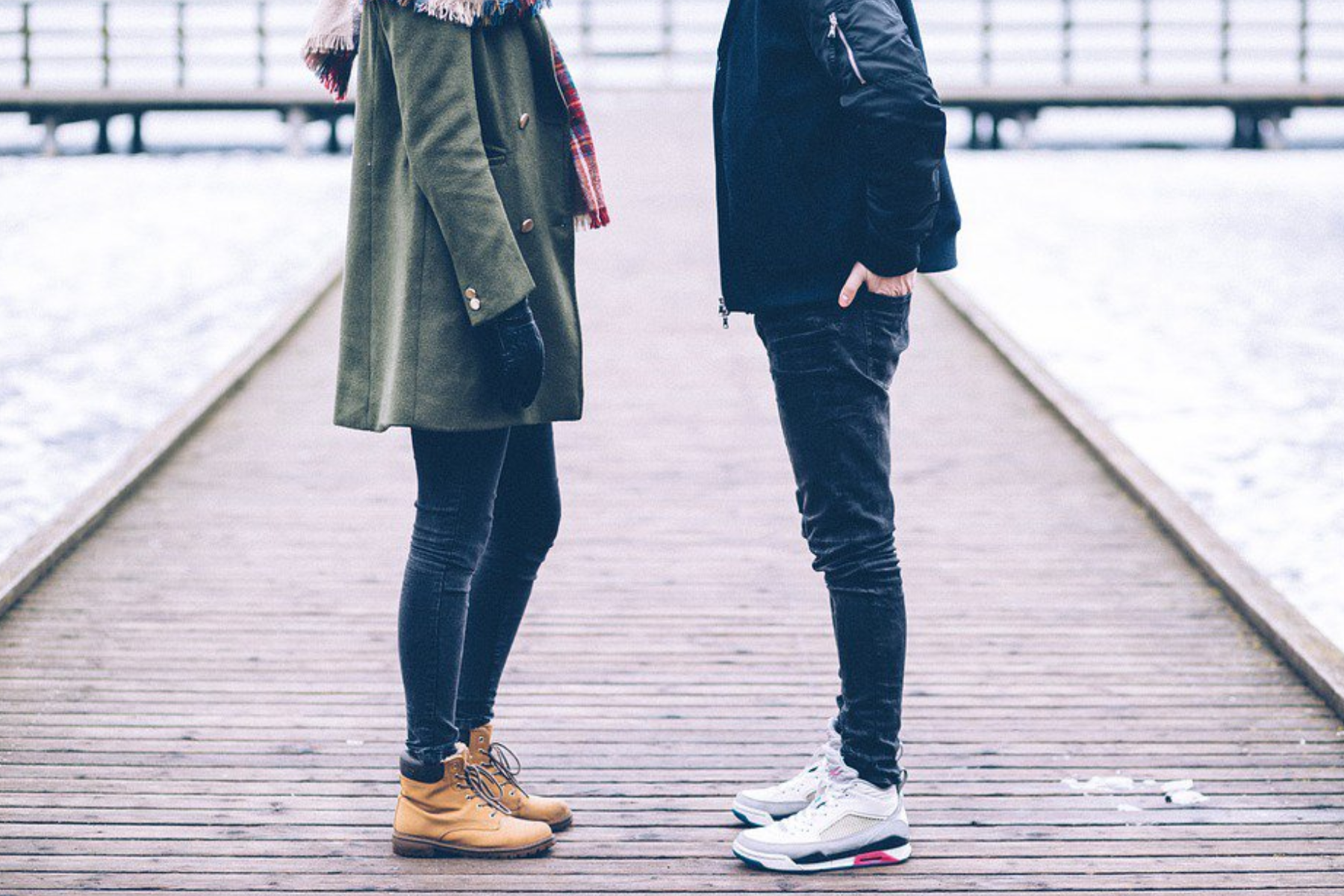 A woman and a man stand on a boardwalk facing each other