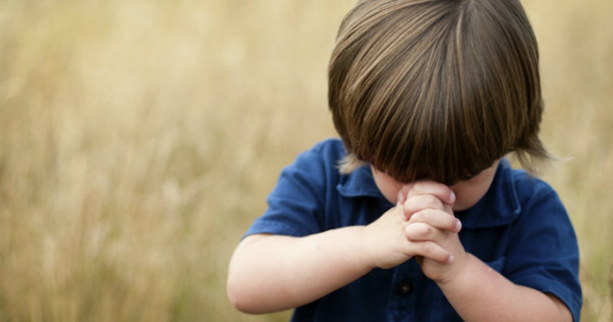 A boy in blue shirt praying