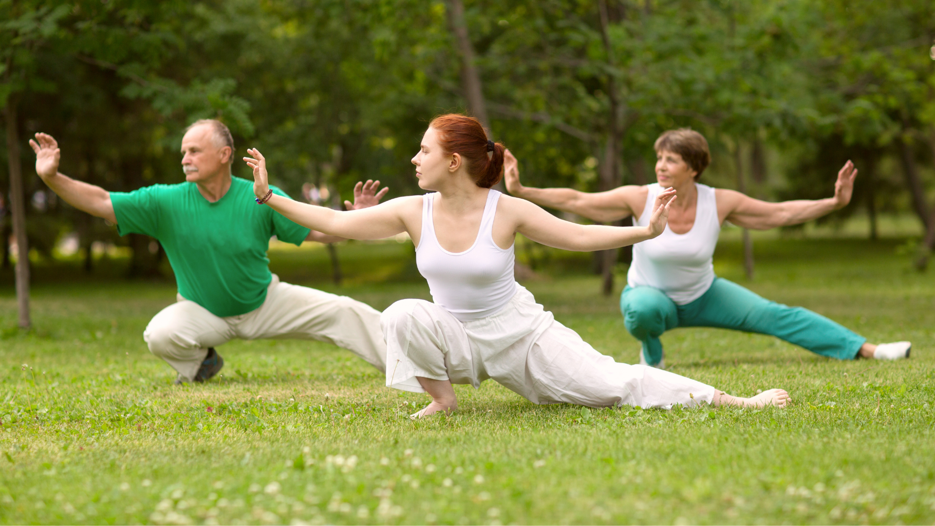 Three people doing yoga on a grass field