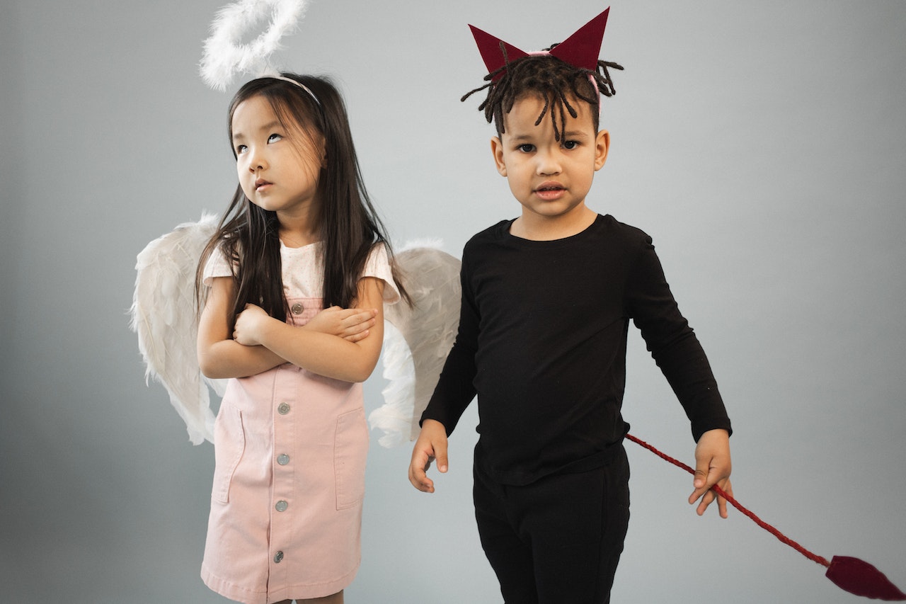 Cute kids in angel and devil costumes