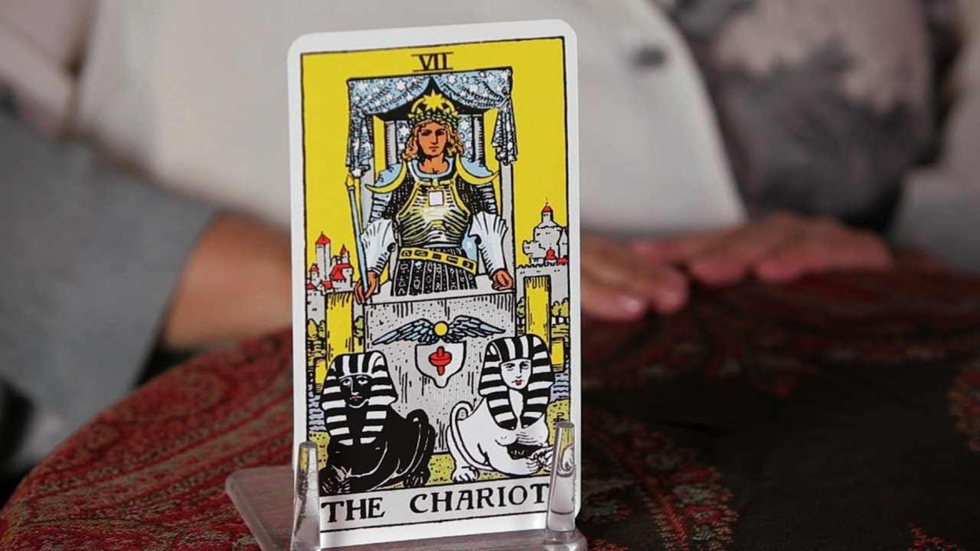 A Chariot Tarot Card places on top of a red table