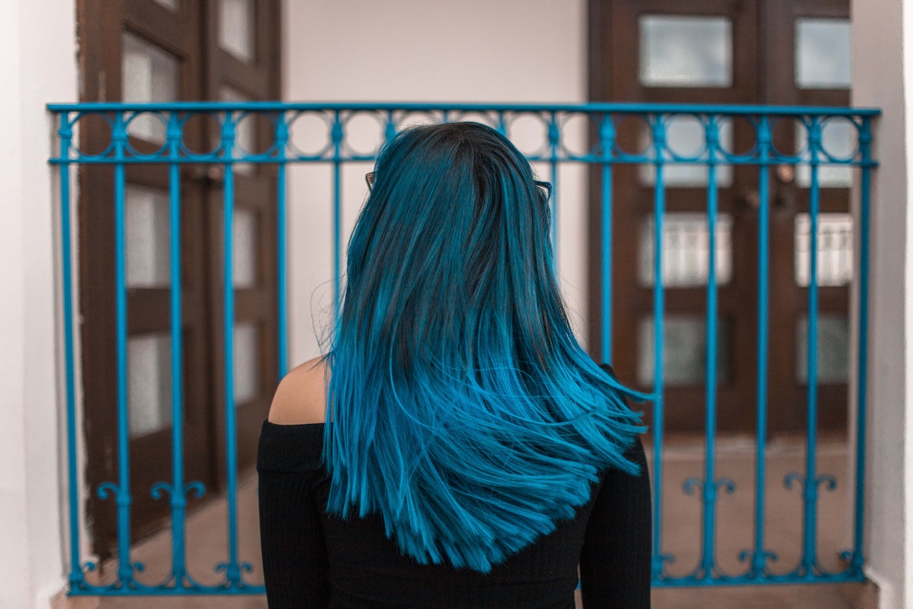 Blue-Haired Woman Facing Metal Fence
