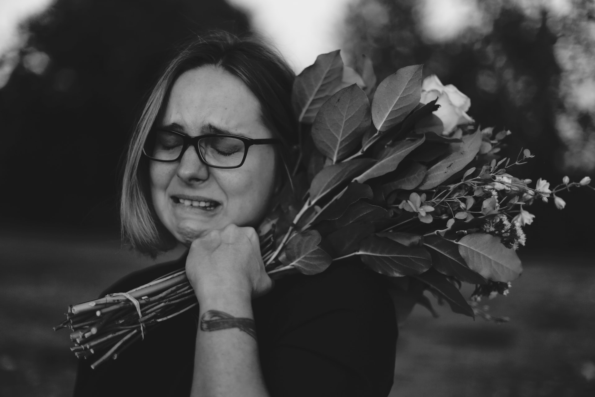 A lady crying while holding a bunch of flowers on her shoulder