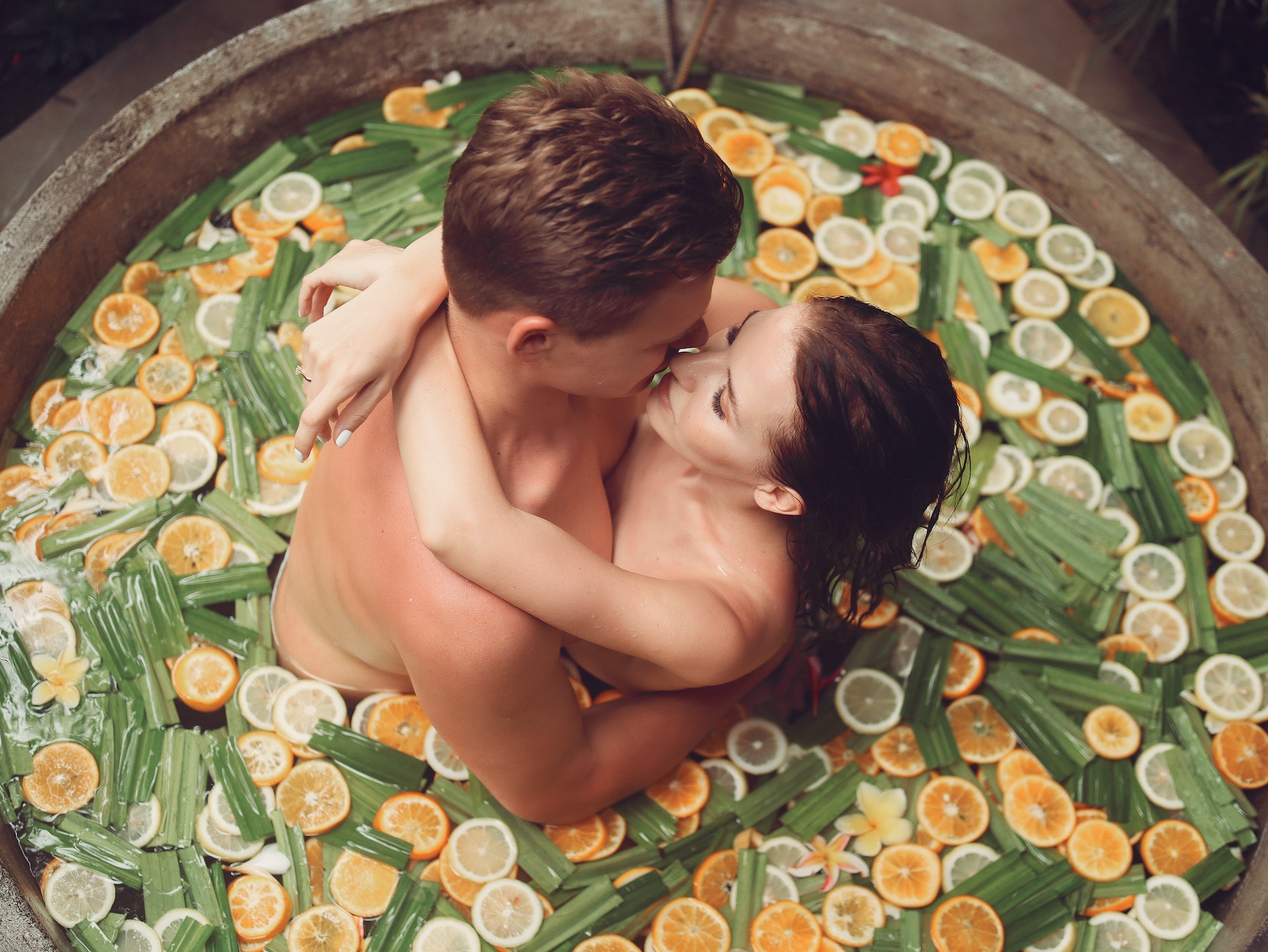 A man and a woman having a sexual encounter in a bath tub filled with sliced fruits
