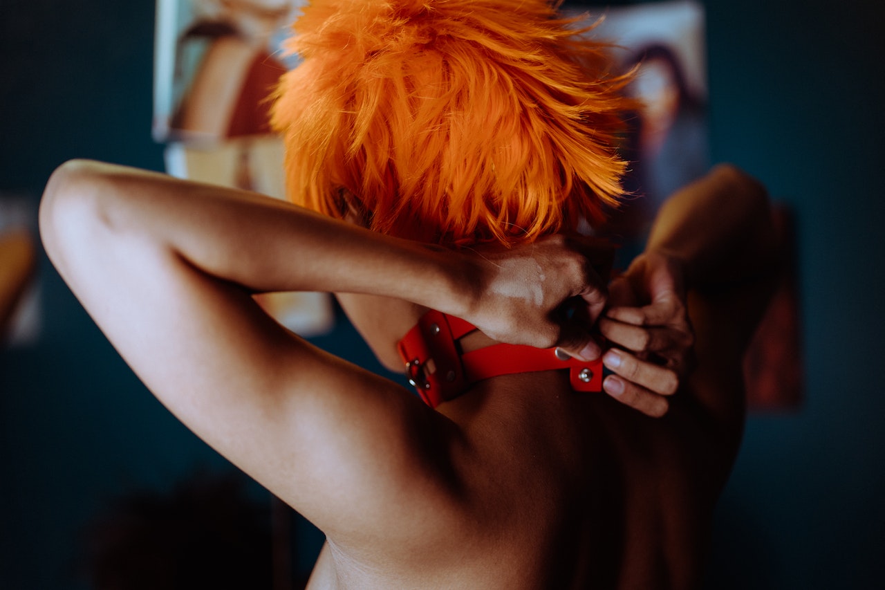 Woman with orange hair putting on choker