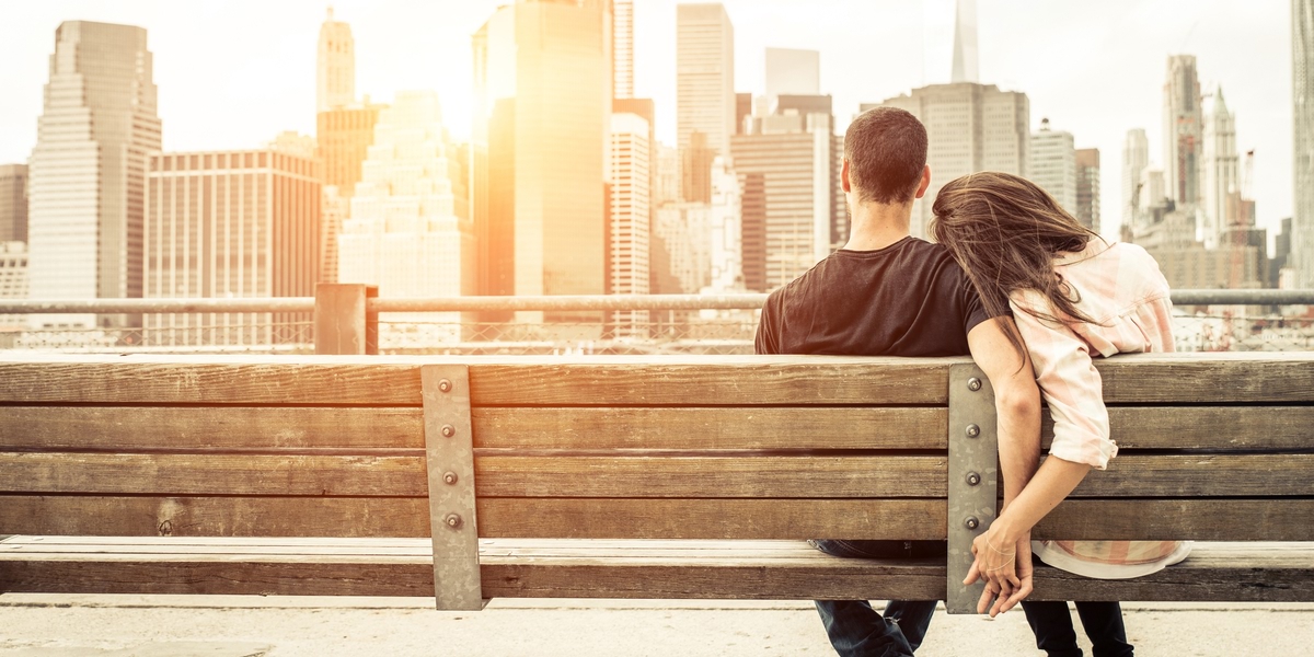 A man and woman sitting in a bench while holding hands