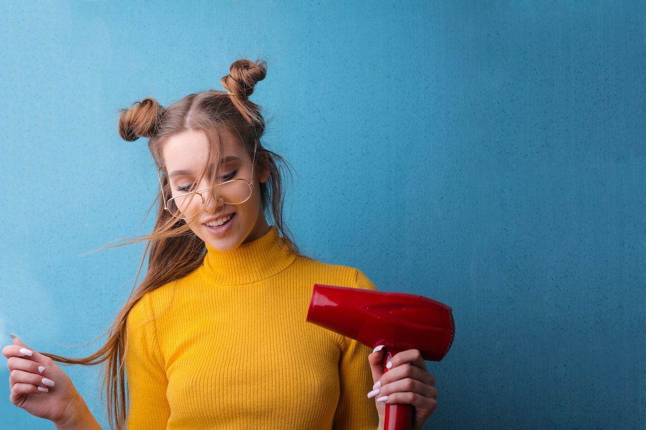 Woman in Yellow Sweater Using Hairdryer