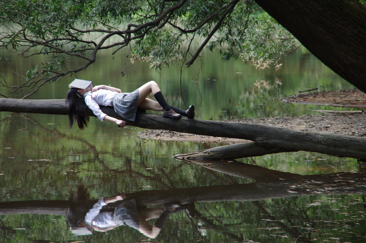 Woman lying on a tree branch over the lake