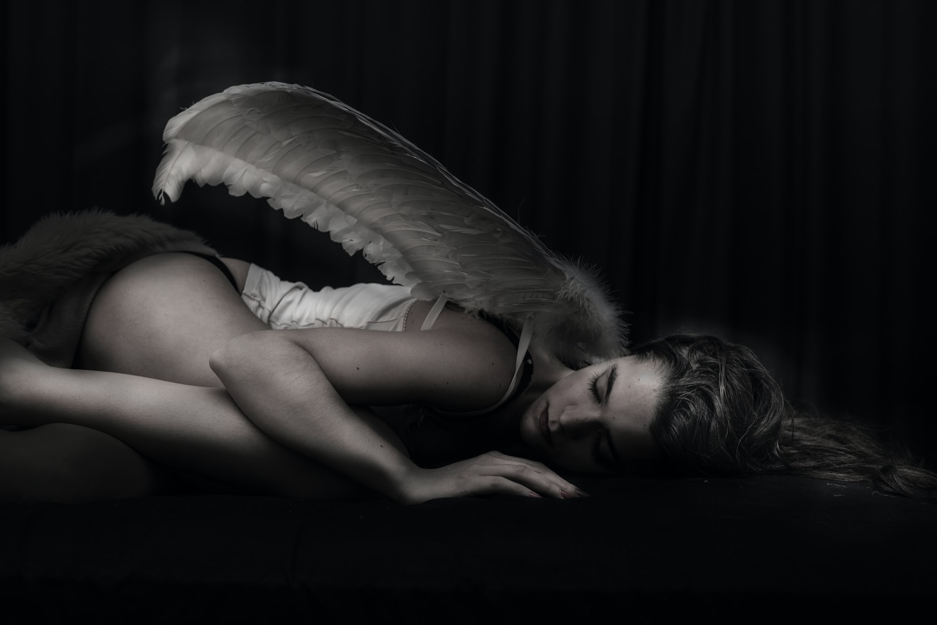 Women With Wings Lying In A Dark Room