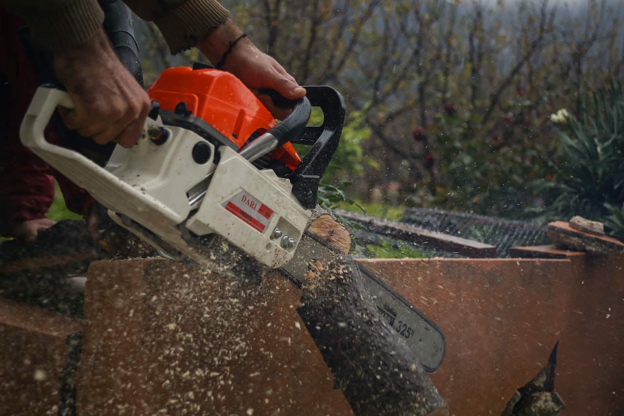 A Man Cutting a Wood Using Chainsaw