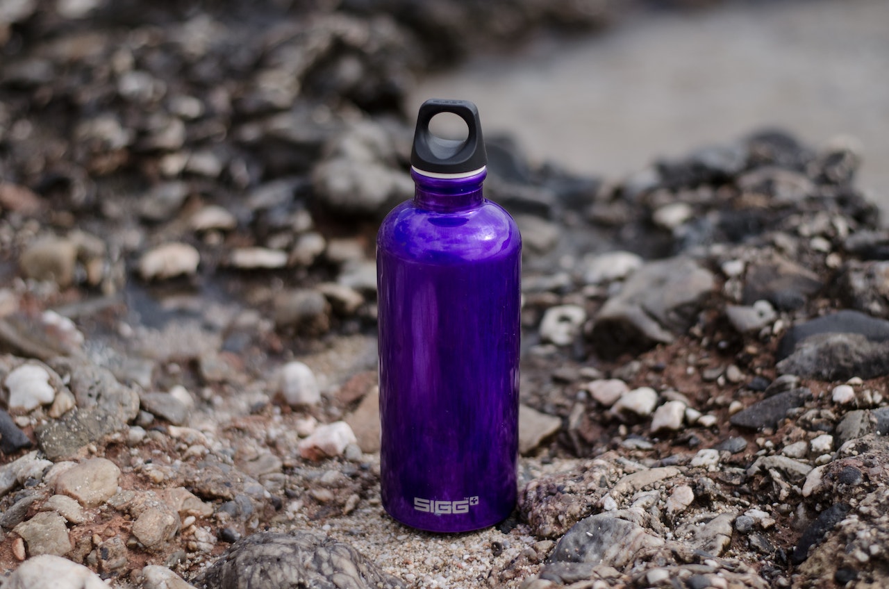 Purple Sports Bottle on a Rocky Ground
