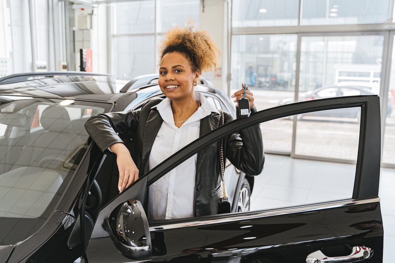 Woman in Black Blazer Standing Beside A Black Car