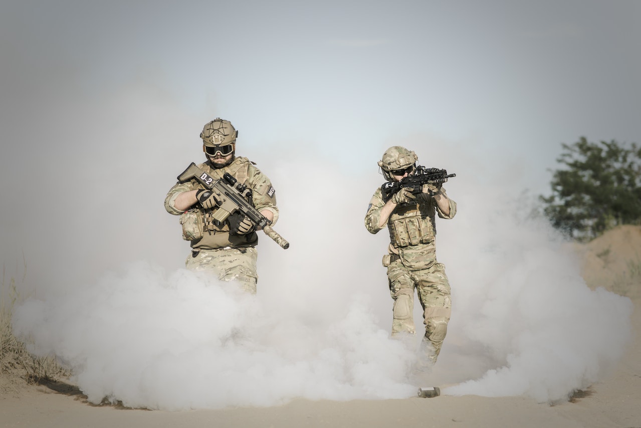 Men Holding Rifles While Walking Through Smoke Grenade