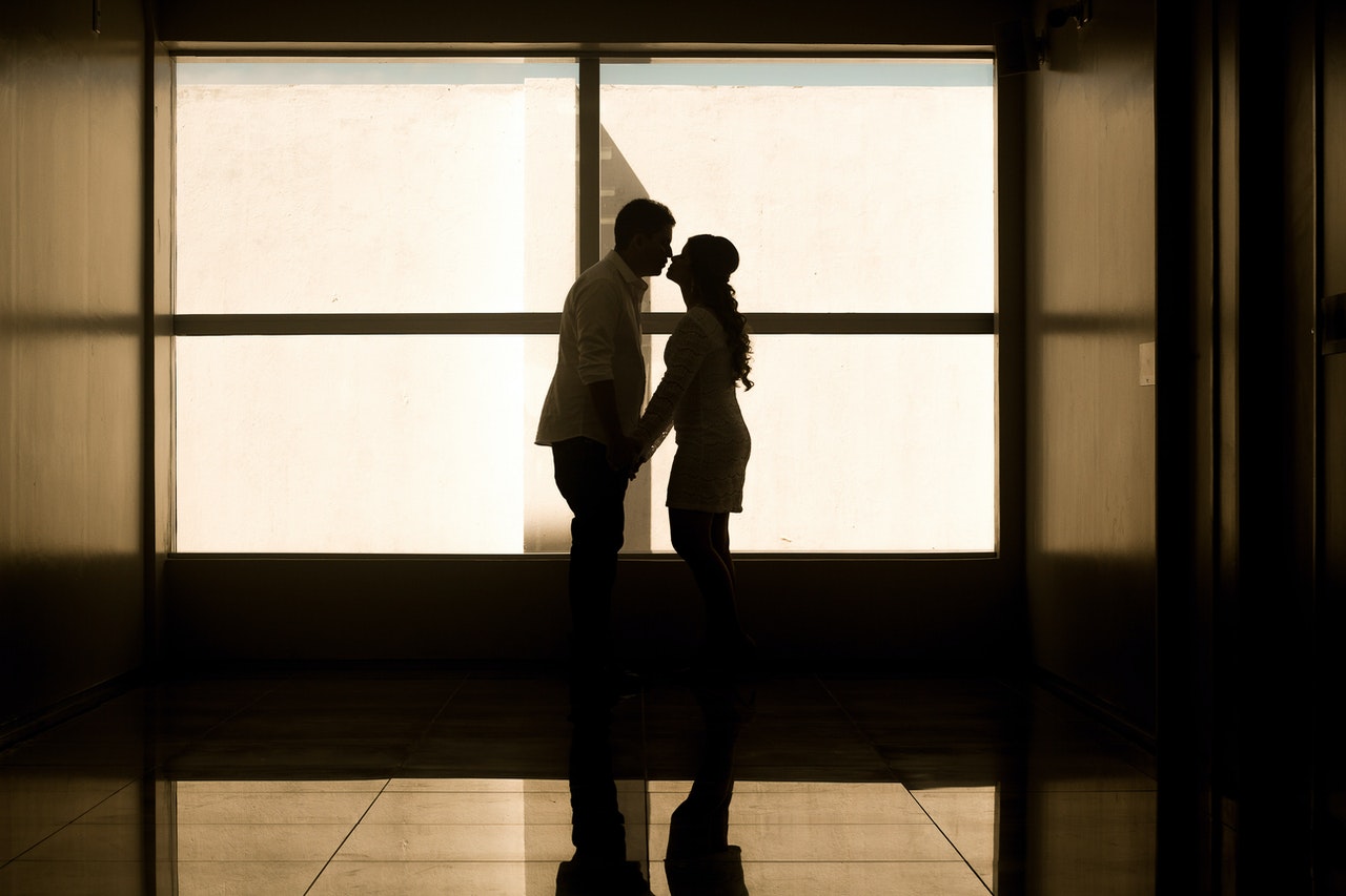 Man and Woman Holding Hands Near Glass Window