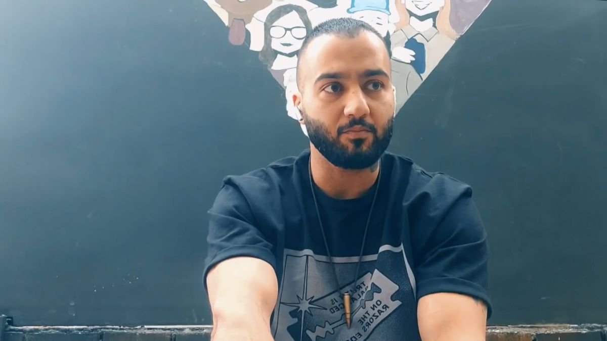 Iran rapper Toomaj Salehi wearing a blue t-shirt while sitting