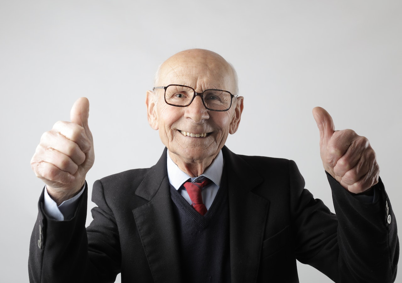 Positive senior man in eyeglasses showing two thumbs up