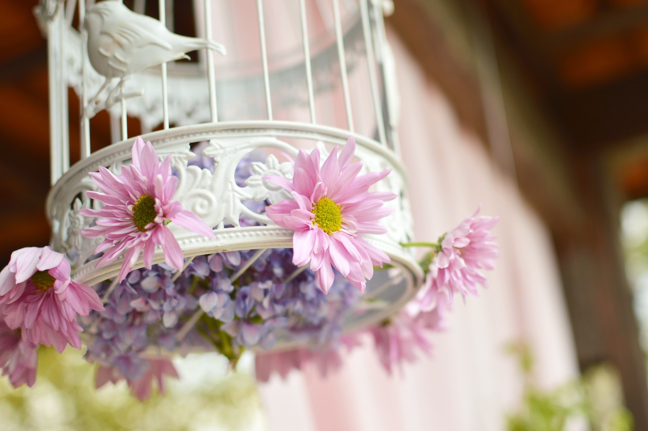A white bird cage with pink and purple flowers on it