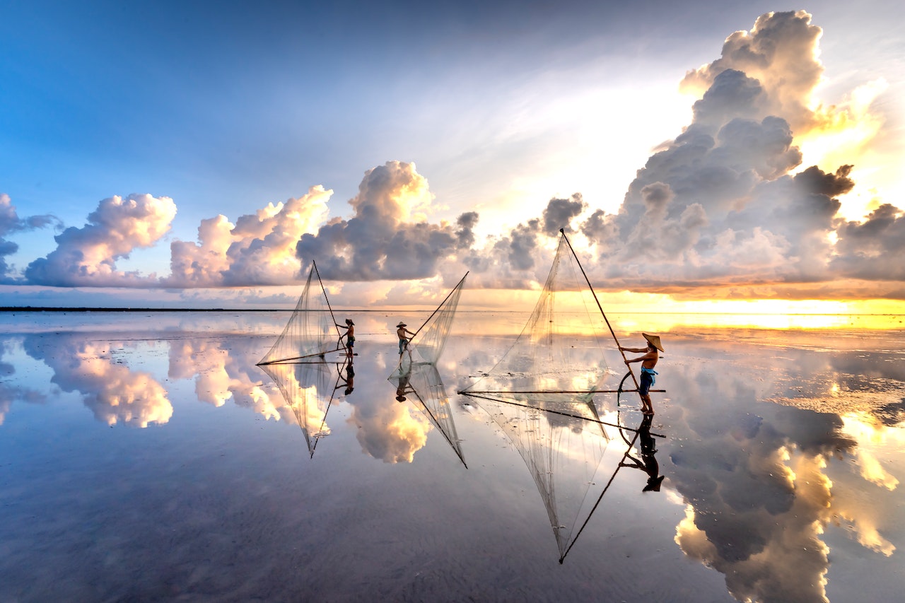 Clouds at Sunset Reflecting in the Sea Where Men Are Catching Fish