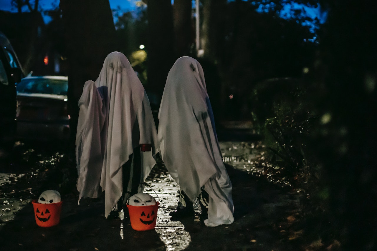 Children Standing Covered With White Blankets Painted Like Ghosts For Halloween Celebration