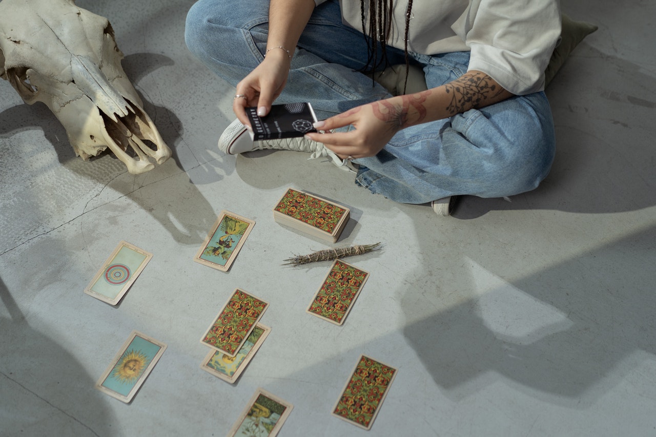 Woman Reading Tarot Cards While Sitting on the Floor
