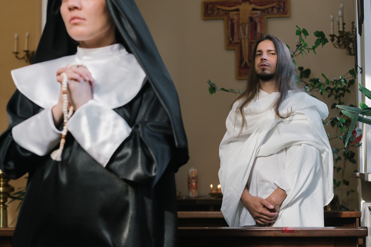 A Man Standing Behind a Praying Nun