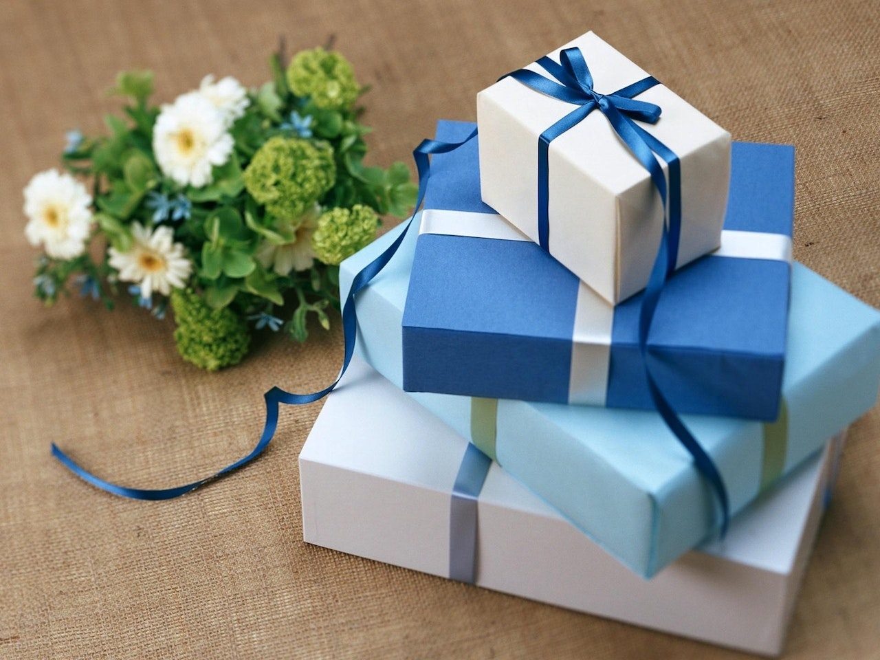Stacked Blue And White Colored Gift Boxes with flowers beside it