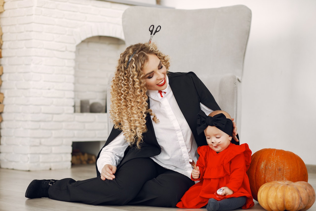 Woman Sitting with Her Daughter in Halloween Costumes 