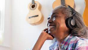 An old black lady joyfully listening to music on headphones