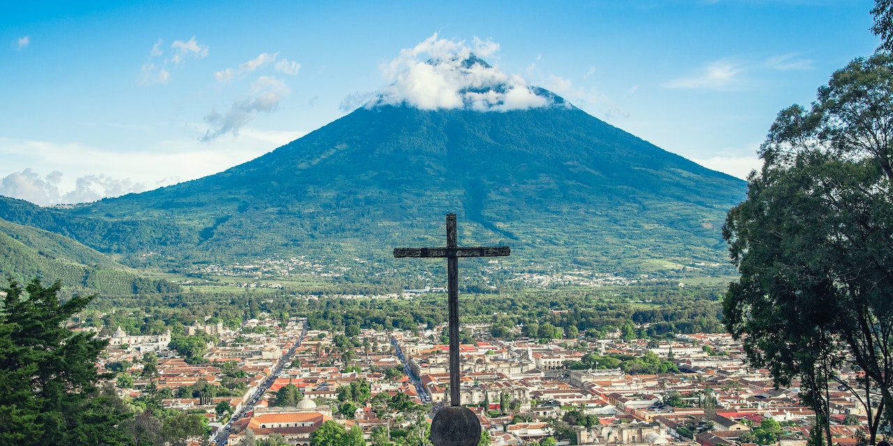 Aerial View of a City, Volcano, And A Cross