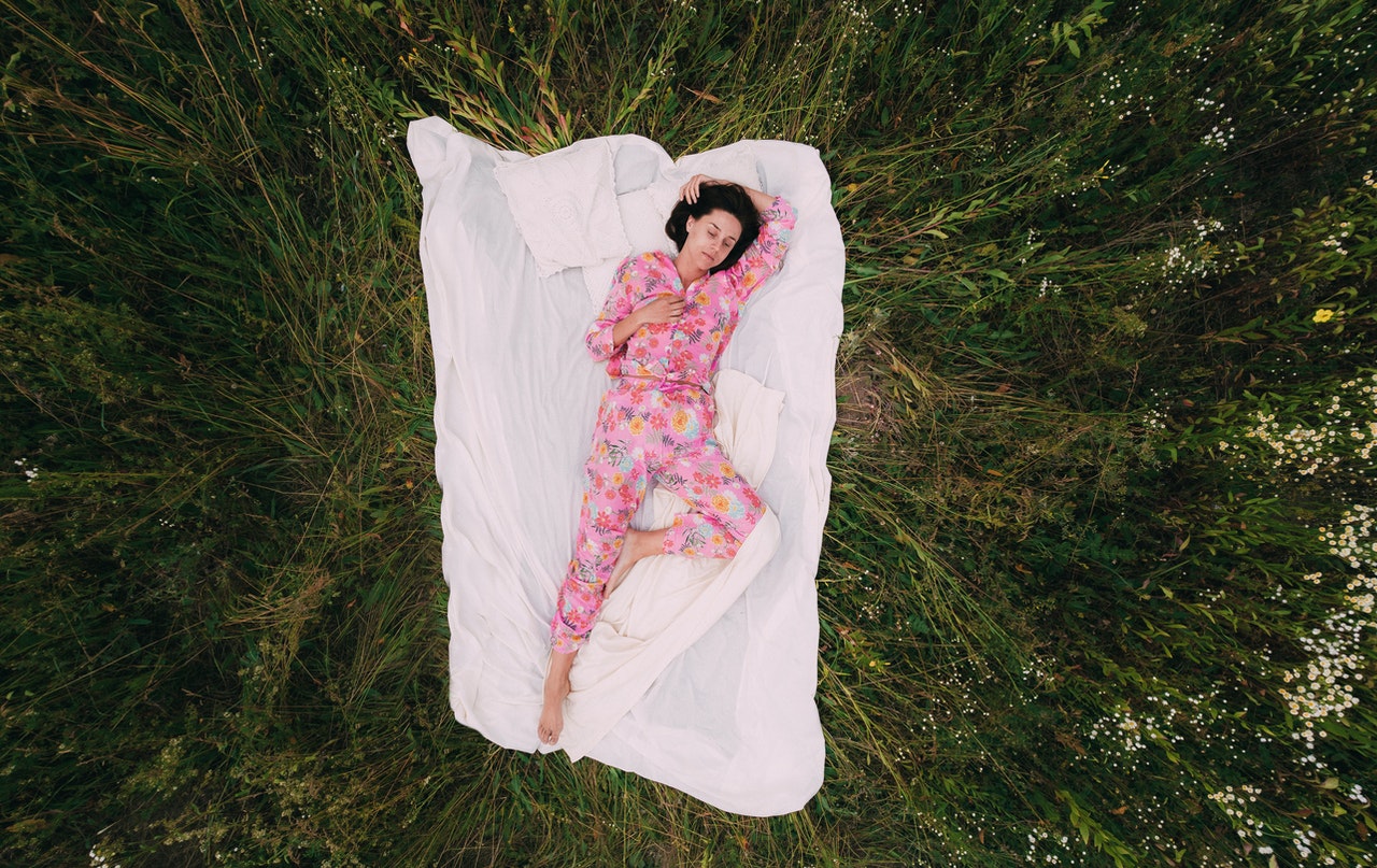 Woman In Pink Floral Pajama Lying On White Textile