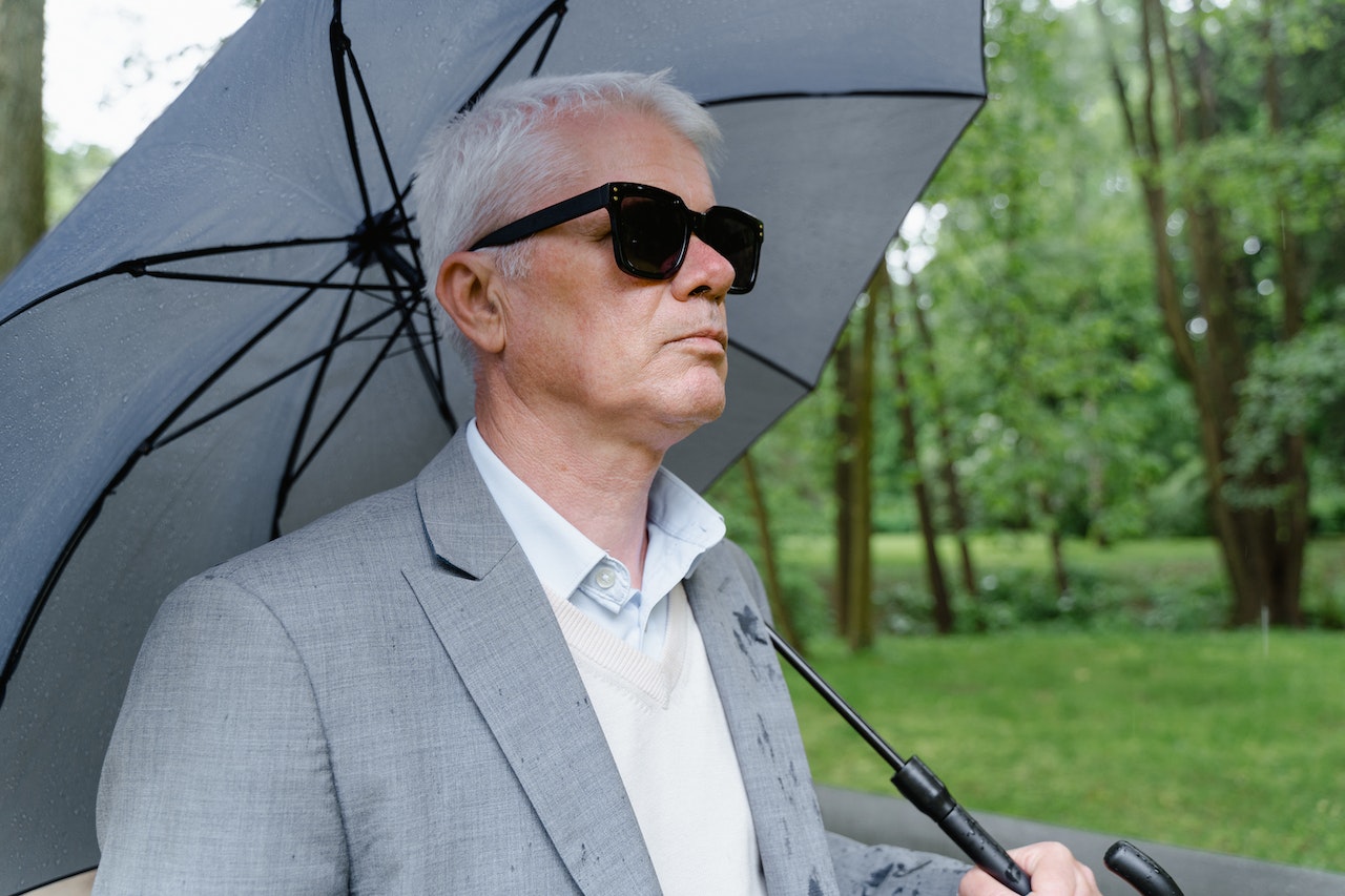 A Man Wearing Sunglasses while Using Umbrella