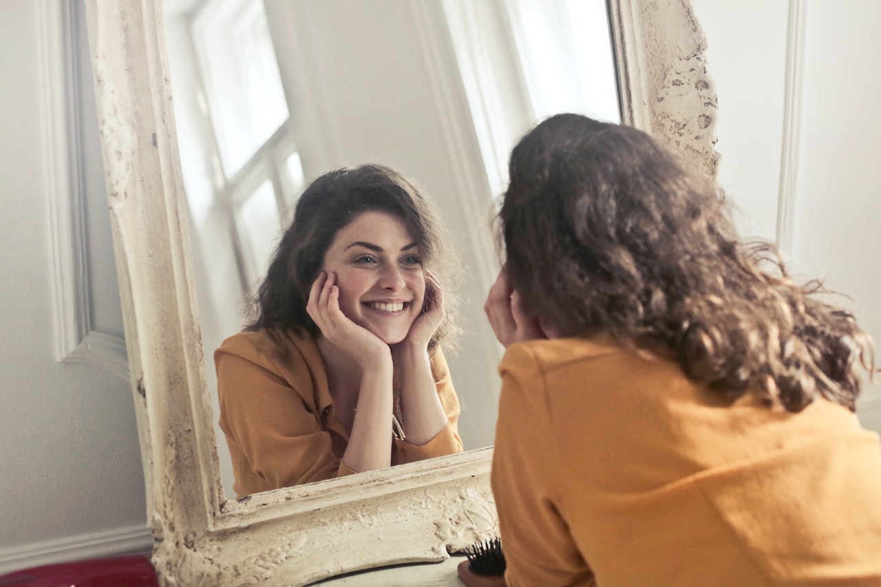 Woman Looking At the Mirror While Smiling