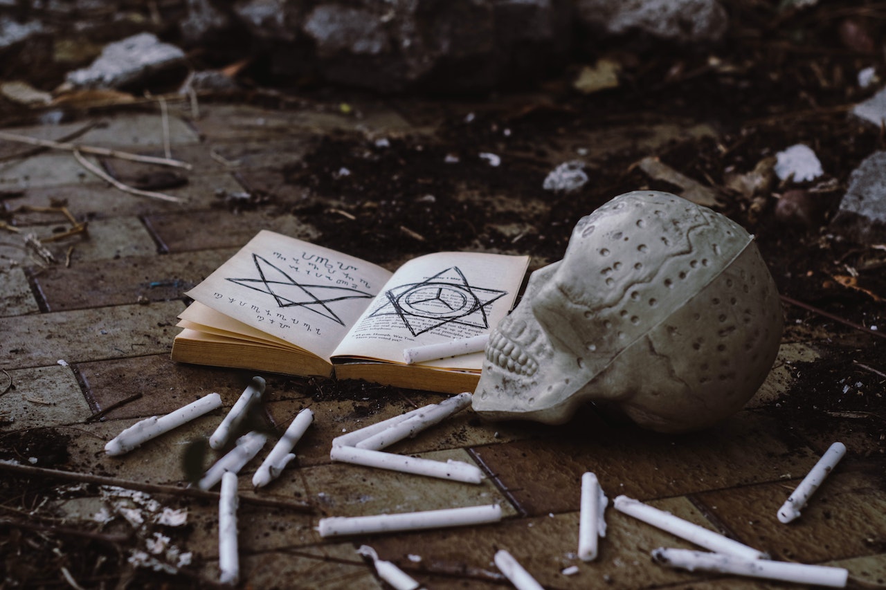 Opened Book Of A Witch Near A Skull With Scattered Candles