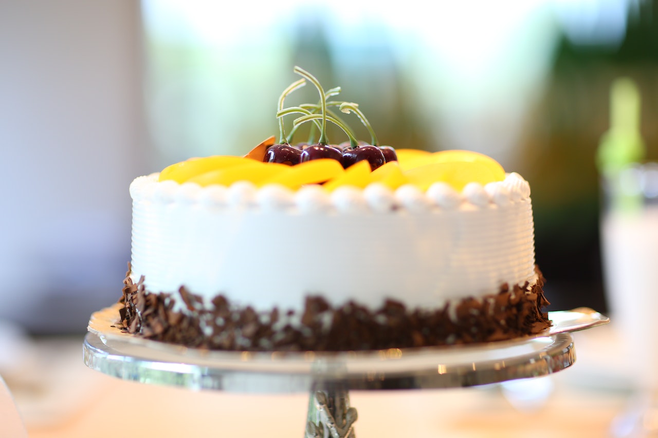White Round birthday Cake Topped With Yellow Slice Fruit