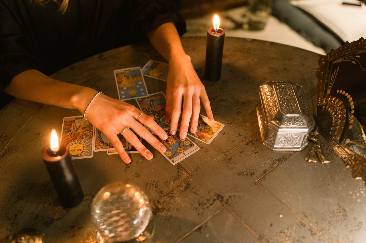Hands Touching the Tarot Cards on the Table With Candles