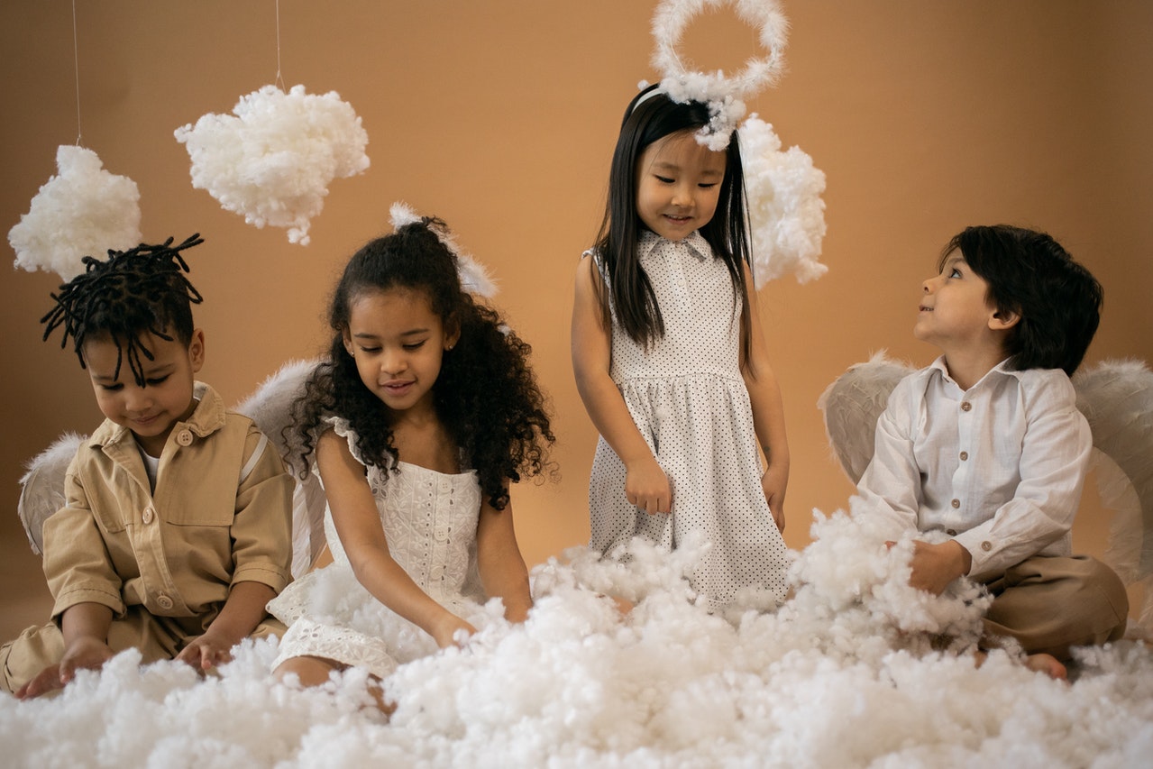 Children in angel costumes playing with cotton wool