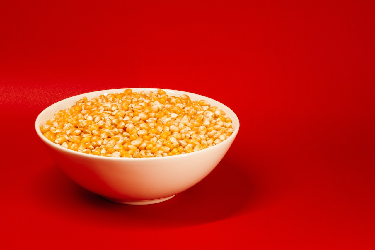 A Bowl of Corn Kernels On A Red Background